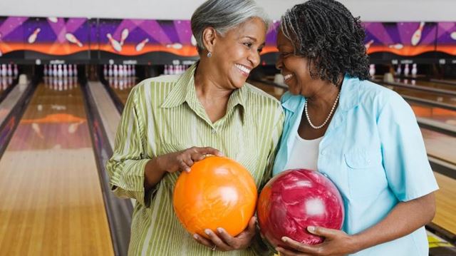 Two women smiling with bowling balls